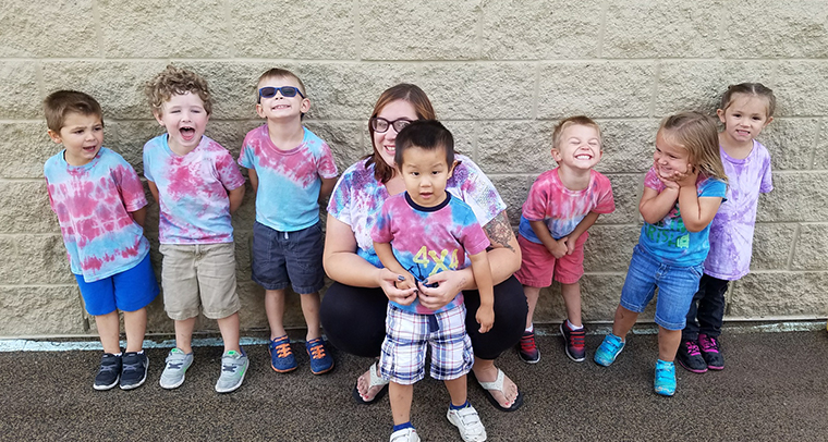 Child care staff member and group of kids wearing tie dye shirts