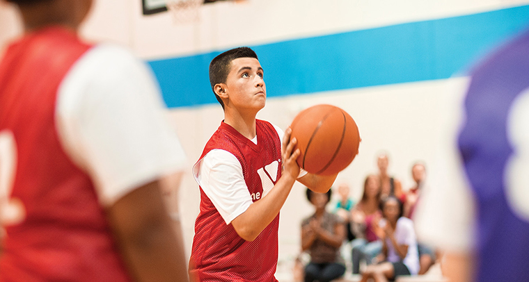 Teen boy on basketball court shooting a basket